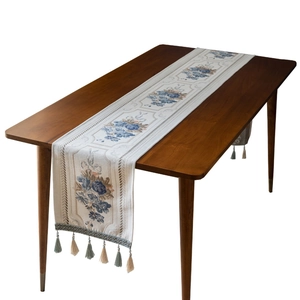 Elegant floral jacquard table runner with tassels on a dark wood dining table