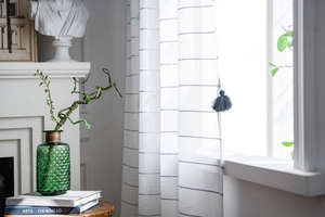 Detail of semi-transparent white curtain with thin black stripes and fringe ball tassel