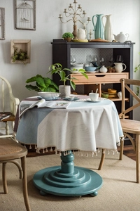 Detail einer runden Tischdecke in Leinenoptik mit blau-beigem Patchwork und Fransen