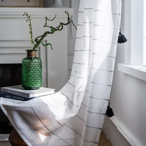 Modern white striped sheer curtain with black tassel fringe decoration and soft lighting