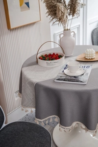 Detail of grey geometric jacquard tablecloth featuring elegant beige tassel trim edge