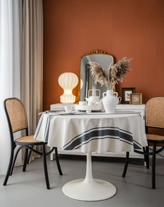Close-up of round linen tablecloth featuring navy blue stripes on a natural beige fabric