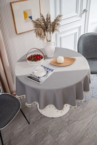 Detail of round grey tablecloth with white geometric patterns and tassel fringe edge