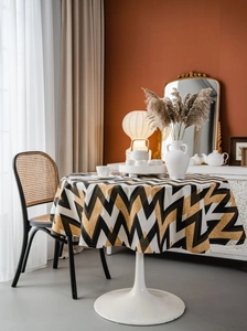 Detail of bohemian round tablecloth with yellow and black wave patterns on a white table