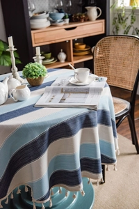 Detailed view of blue striped cotton linen tablecloth with elegant cream fringe tassels