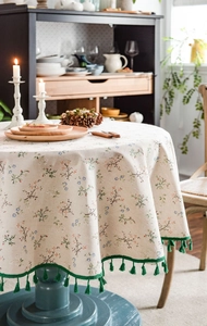Detail of floral round tablecloth with green lace edge and decorative tassel fringe