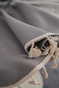 Close-up of grey geometric jacquard tablecloth with textured weave and cream fringe detail