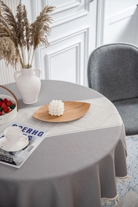 Close-up of grey geometric jacquard tablecloth with cream tassels and rustic decor