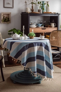 Close-up of blue striped round tablecloth with elegant fringe tassels and cotton-linen texture