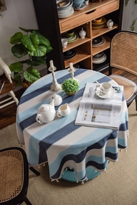 Close-up of blue and white striped round tablecloth featuring delicate white fringe tassels