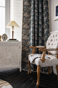 Detail of vintage blue floral curtains with fringe tassels in a French country room setting