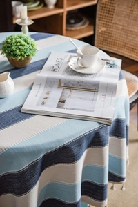 Close-up of blue striped tablecloth with thick linen texture and cream fringe trim