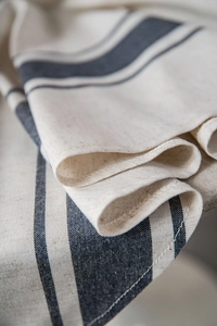 Detailed close-up of textured navy striped cotton linen fabric with refined hemmed edges