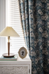 Detailed close-up of blue floral jacquard curtain fabric with elegant fringe tassels