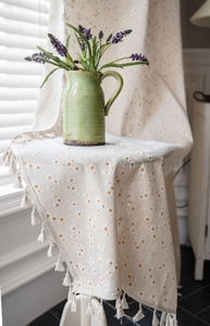 Detailed macro view of pastoral daisy print on beige cotton linen fabric with tassel edges
