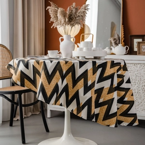 Bohemian round tablecloth with gold and black zigzag geometric patterns on a dining table