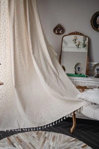 Detail of vintage linen curtain with daisy floral prints and white tassel fringe trim
