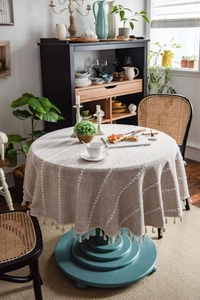 Detail of round cotton linen tablecloth with white embroidery and tassel fringe