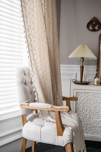 Detailed texture of cotton linen curtain with daisy print and elegant pom-pom fringe trim