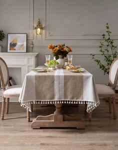 Detail showing khaki and beige linen tablecloth with hollow embroidery and white tassels