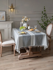 Detail of grey linen-textured tablecloth with woven patterns and elegant white fringe edges