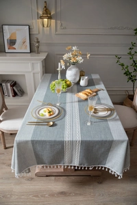 Detail of grey-blue linen tablecloth with white tassels and woven geometric patterns