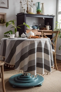 Close-up of grey striped round tablecloth with elegant fringe tassels in a cozy dining setting