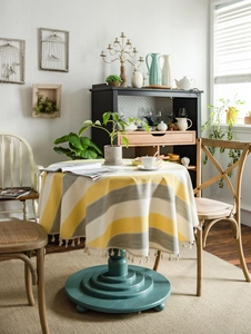 Detail of yellow and grey striped tablecloth with white tassel fringe on round table