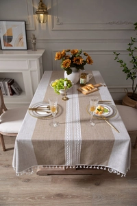 Detail of linen style striped tablecloth with white tassel fringe and floral embroidery