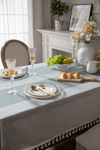Close-up of grey cotton linen tablecloth featuring white lace inlay and elegant fringe trim