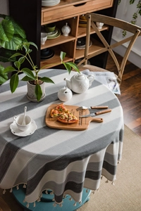 Close-up of Nordic round tablecloth featuring grey stripes and decorative white tassels