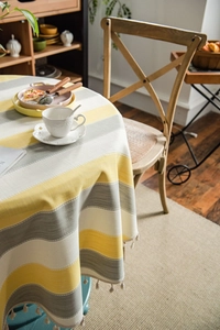 Detail of yellow and grey striped tablecloth showing cotton linen texture and beige tassels