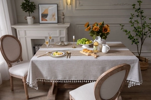 Detail of rectangular linen-blend tablecloth featuring brown patchwork and white tassels