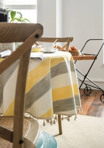 Close-up of yellow and grey striped tablecloth fabric with elegant fringe tassels detail