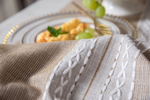 Macro view of brown striped linen tablecloth with handcrafted X-shaped embroidery