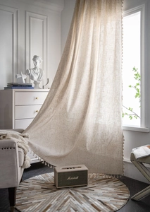 Close-up of beige linen curtain fabric featuring elegant fringe tassel edge trim details