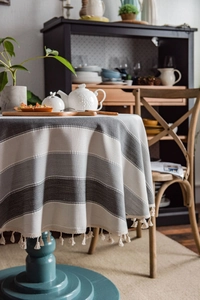 Detail of grey striped tablecloth fabric texture with decorative off-white tassels