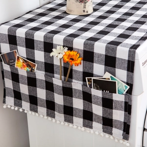 Detail of black and white plaid dust cover with storage pocket and white pom-pom trim