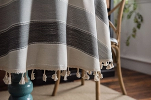 Close-up of grey striped tablecloth fabric with elegant off-white tassel fringe detail