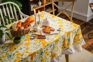 Detail of floral tablecloth with yellow blossoms and elegant white ruffled edge