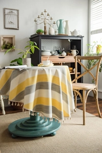 Close-up of yellow and gray striped round tablecloth with elegant tassel fringe details