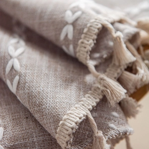 Linen tablecloth with white embroidery and tassel fringe in a cozy Nordic style