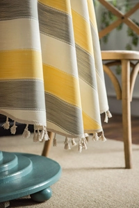Detail of yellow and gray striped tablecloth showing thick texture and fringe tassels