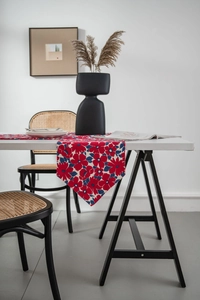 Detail of red floral table runner with pointed ends on a modern minimalist wooden table