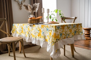 Detail shot of pastoral yellow floral tablecloth with wide white ruffled edges and fabric texture