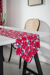 Detail of red floral table runner on a white desk with home decor accessories