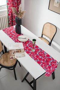 Detail of red floral table runner with intricate botanical patterns on white wooden table