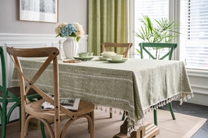 Detail of green cotton linen tablecloth with white diamond weave and fringe tassels