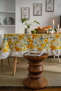 Detailed view of yellow floral pattern tablecloth featuring elegant white ruffled edges