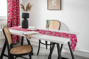 Detail of red floral table runner with matching curtain and decorative green pom pom fringe